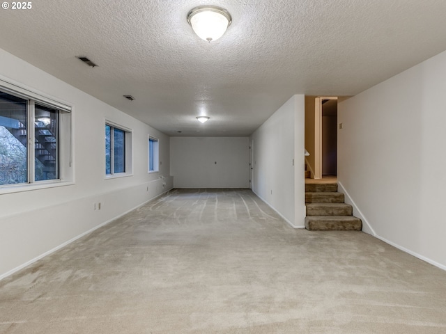 spare room with light colored carpet and a textured ceiling