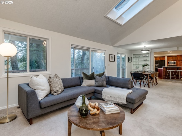 living room featuring carpet, high vaulted ceiling, and a skylight