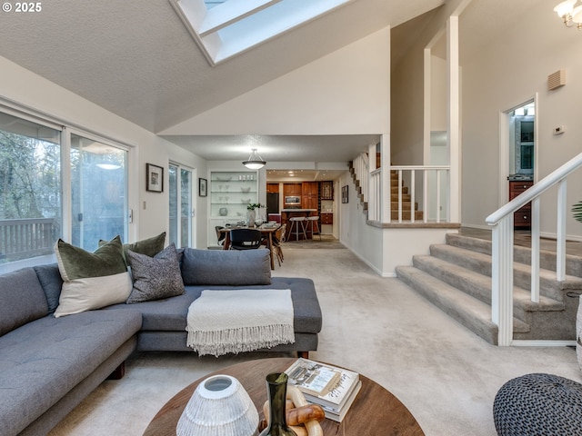 living room with a textured ceiling, a skylight, high vaulted ceiling, and light colored carpet