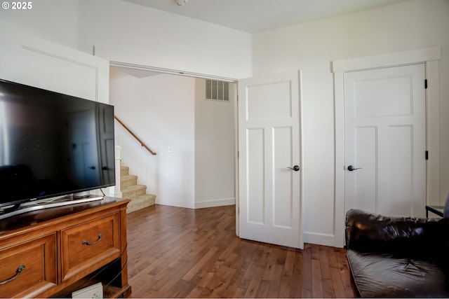 living area with visible vents, baseboards, hardwood / wood-style flooring, and stairs