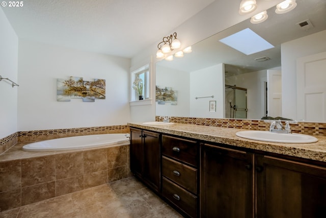 full bath featuring a sink, a shower stall, visible vents, a skylight, and a garden tub