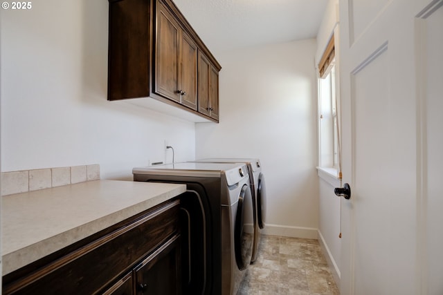 washroom featuring cabinet space, baseboards, stone finish floor, and separate washer and dryer
