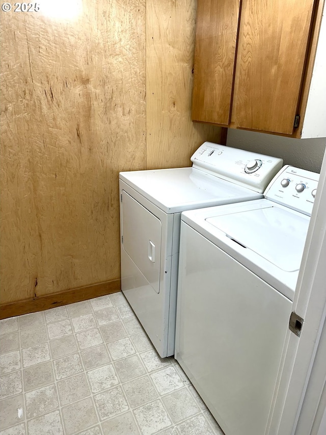 clothes washing area with washing machine and dryer, baseboards, cabinet space, and light floors