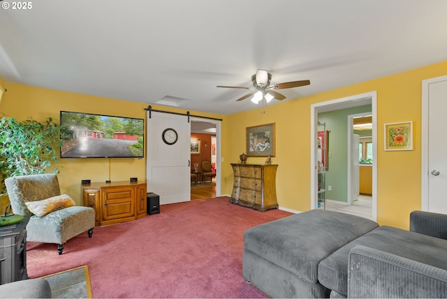carpeted living room with a barn door and a ceiling fan