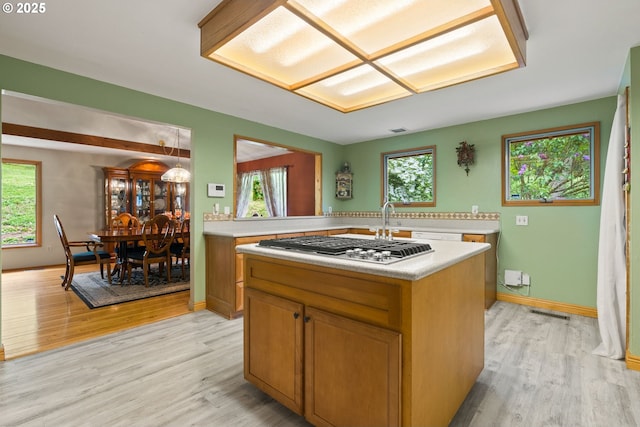 kitchen featuring light countertops, stainless steel gas cooktop, light wood-style flooring, and a center island