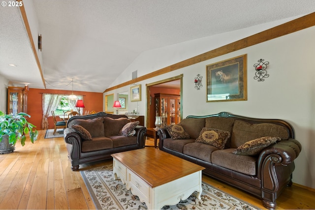 living area with hardwood / wood-style flooring, vaulted ceiling, a chandelier, and a textured ceiling