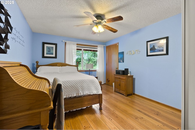 bedroom featuring light wood finished floors, a textured ceiling, ceiling fan, and baseboards