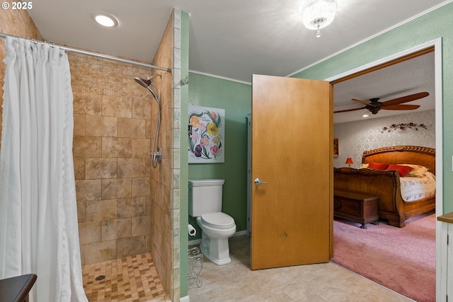 ensuite bathroom with ceiling fan, a tile shower, toilet, and crown molding