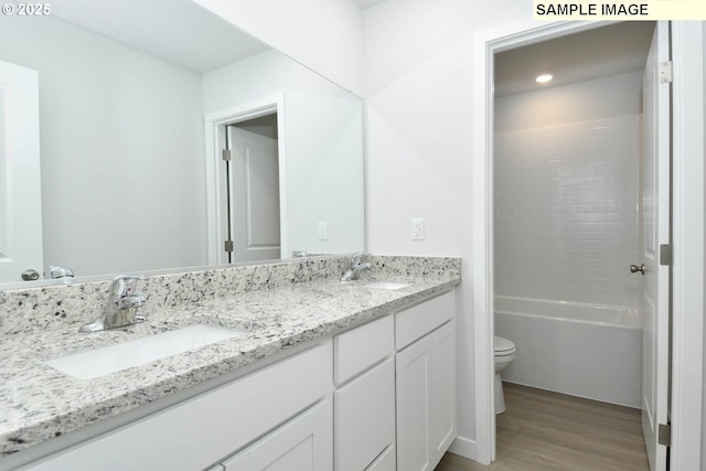 full bathroom with hardwood / wood-style flooring, vanity, toilet, and shower / washtub combination