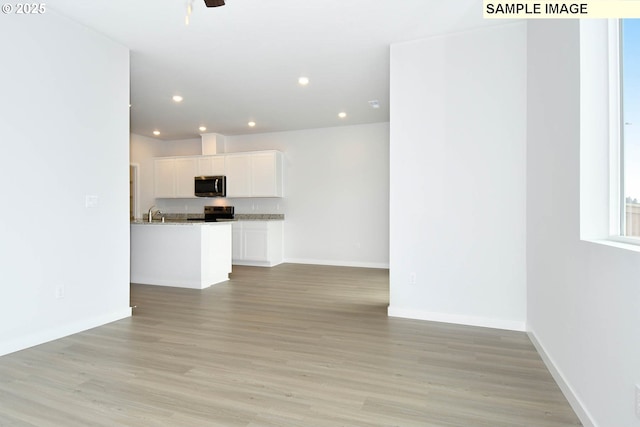 unfurnished living room with sink, light hardwood / wood-style floors, and ceiling fan