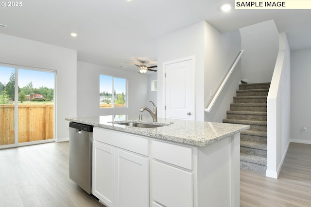 kitchen with sink, stainless steel dishwasher, an island with sink, light stone countertops, and white cabinets