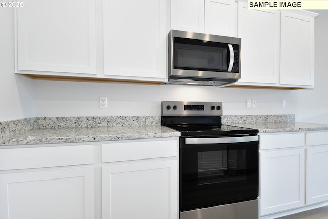 kitchen featuring white cabinetry, appliances with stainless steel finishes, and light stone counters