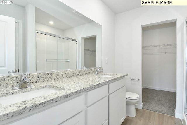 bathroom with vanity, wood-type flooring, a shower with door, and toilet