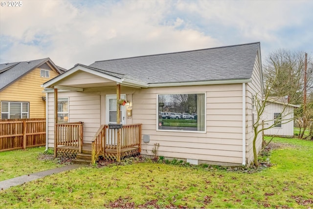 view of front of home with a shingled roof, a front yard, and fence