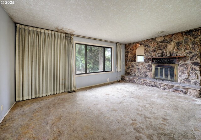 14251 Caufield Rd, Oregon City, OR 97045 - unfurnished living room with a textured ceiling, a stone fireplace, carpet, and baseboards