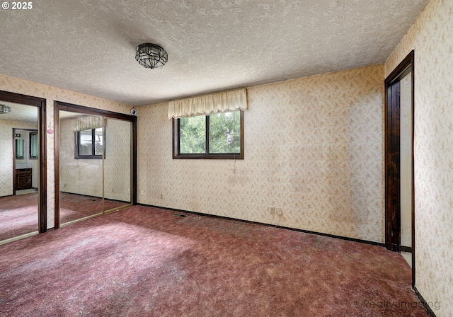 14251 Caufield Rd, Oregon City, OR 97045 - unfurnished bedroom with a textured ceiling, multiple windows, carpet floors, two closets, and wallpapered walls