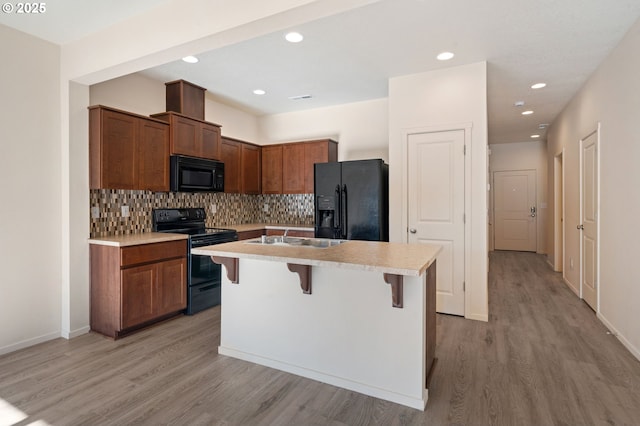 8512 NE 13th Pl, Vancouver, WA 98665 - kitchen featuring black appliances, light countertops, light wood-style floors, a kitchen island with sink, and a breakfast bar
