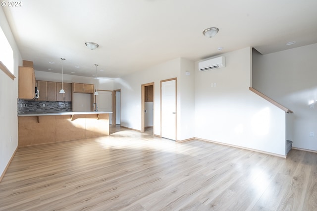 unfurnished living room featuring sink, light wood-type flooring, and an AC wall unit