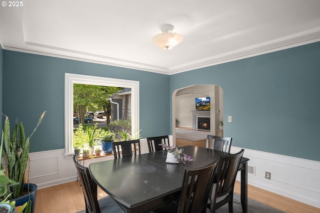 7414 N Chautauqua Blvd, Portland, OR 97217 - dining area with arched walkways, wood finished floors, wainscoting, a warm lit fireplace, and ornamental molding