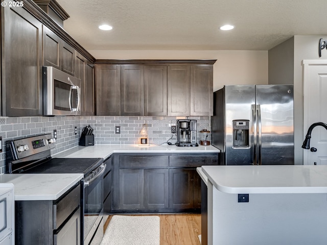 11411 NE 131st Pl, Vancouver, WA 98682 - kitchen with dark brown cabinets, light wood-type flooring, tasteful backsplash, and appliances with stainless steel finishes