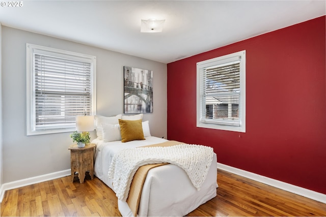 bedroom with multiple windows, baseboards, and wood finished floors