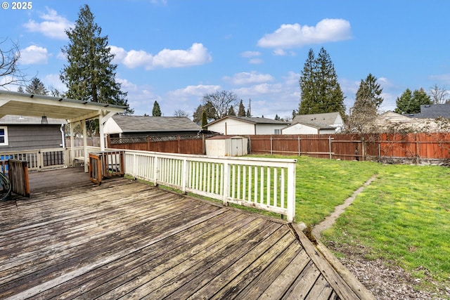 deck with a storage shed, an outbuilding, a lawn, and a fenced backyard