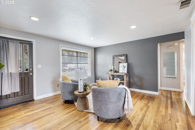 sitting room featuring baseboards, visible vents, light wood-style flooring, recessed lighting, and a textured ceiling