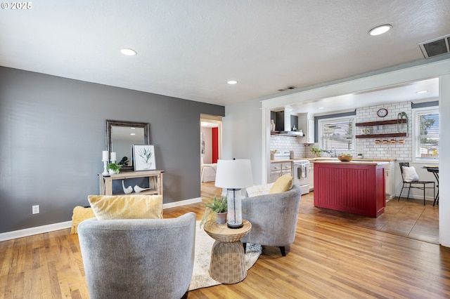 living area with visible vents, baseboards, and light wood-style floors