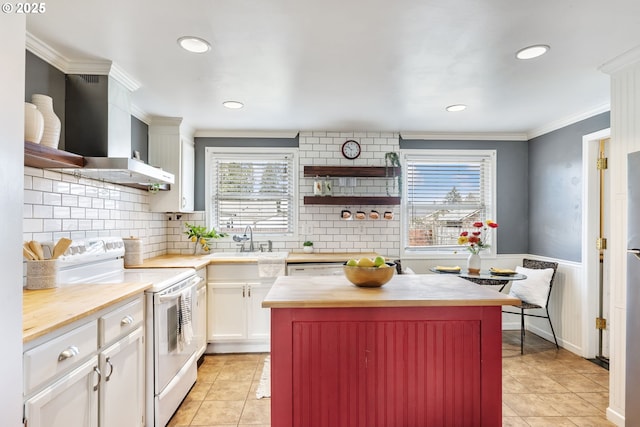 kitchen with wall chimney range hood, butcher block counters, ornamental molding, white electric range oven, and a sink