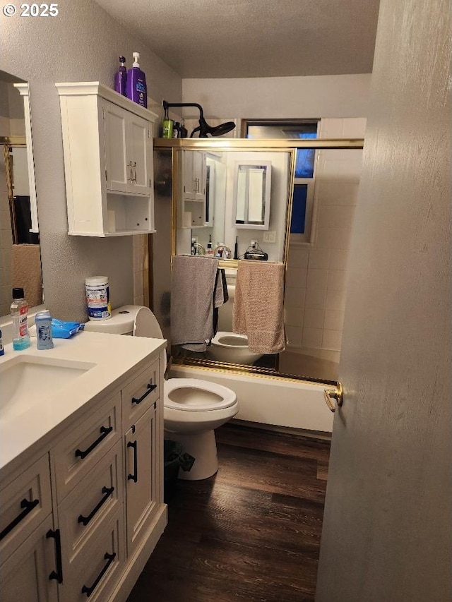 full bathroom featuring hardwood / wood-style floors, vanity, shower / washtub combination, toilet, and a textured ceiling