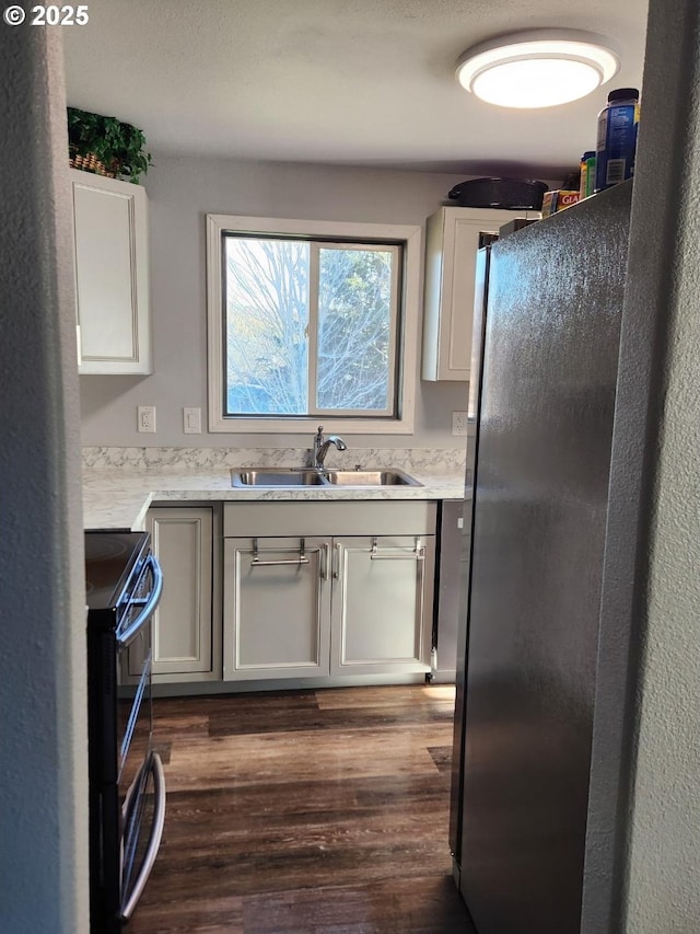 kitchen featuring white cabinetry, sink, dark wood-type flooring, black electric range oven, and fridge