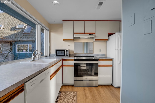 kitchen featuring visible vents, light wood-style flooring, a sink, under cabinet range hood, and stainless steel appliances