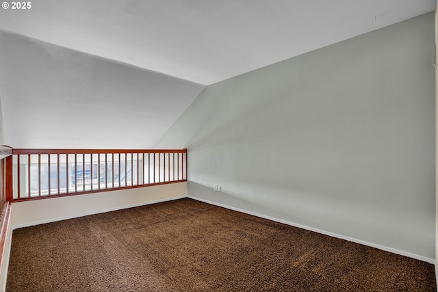 empty room with lofted ceiling, baseboards, and dark colored carpet