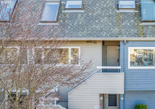 exterior space featuring mansard roof and a shingled roof