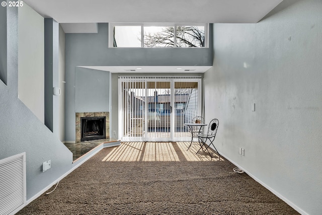 unfurnished living room with visible vents, plenty of natural light, carpet, and a high end fireplace