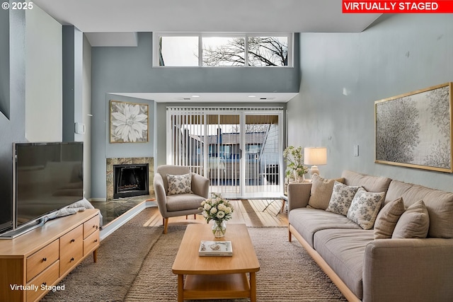 living room with a healthy amount of sunlight, wood finished floors, a towering ceiling, and a premium fireplace