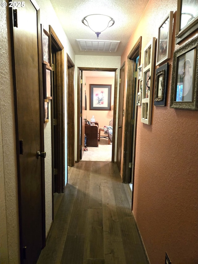 corridor with dark hardwood / wood-style floors and a textured ceiling