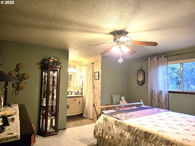 carpeted bedroom with a textured ceiling, ceiling fan, and ensuite bathroom