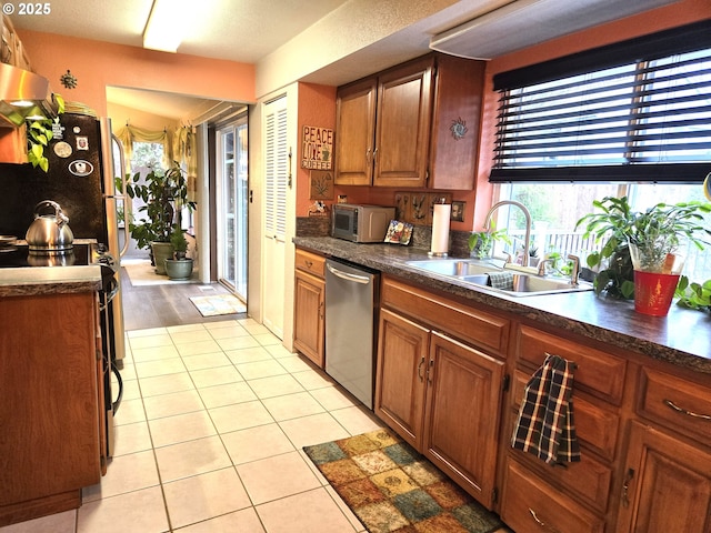 kitchen with light tile patterned flooring, appliances with stainless steel finishes, ventilation hood, and sink