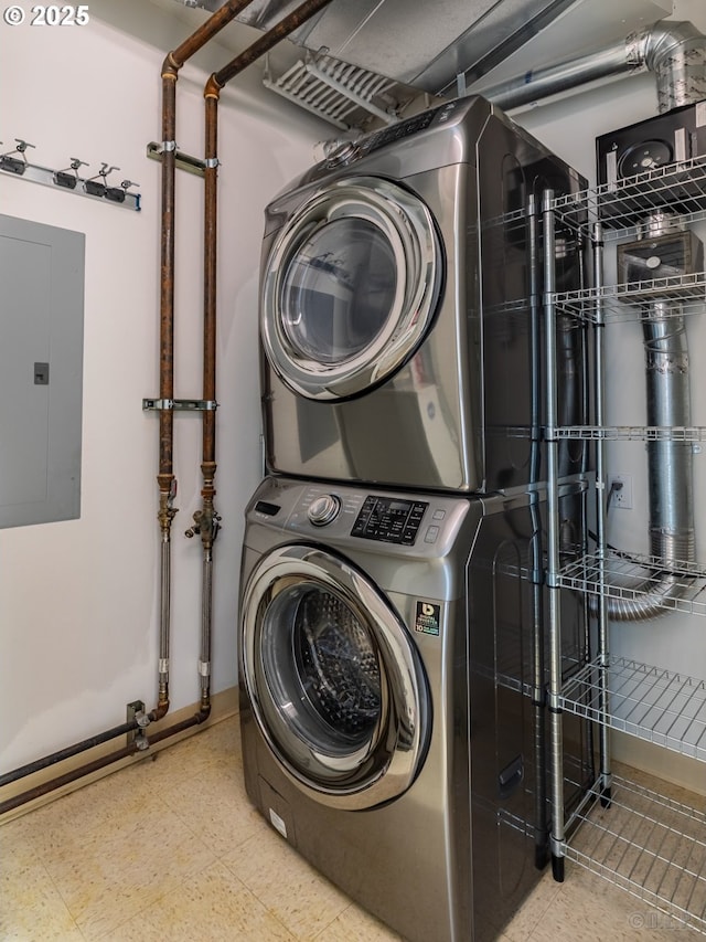 laundry area featuring electric panel and stacked washer and clothes dryer