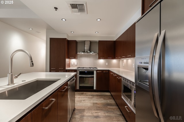 kitchen featuring tasteful backsplash, sink, stainless steel appliances, dark wood-type flooring, and wall chimney range hood