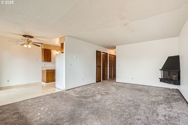 unfurnished living room featuring a textured ceiling, light carpet, and ceiling fan