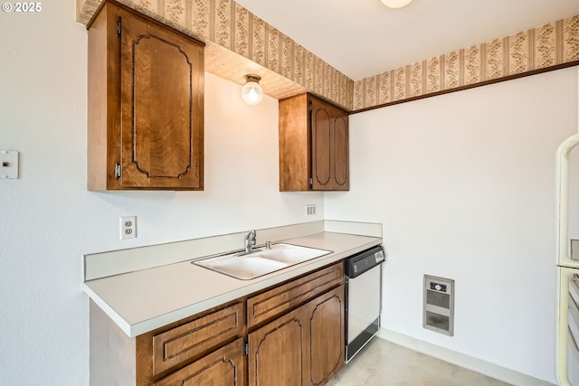 kitchen with a sink, brown cabinets, light countertops, and dishwasher