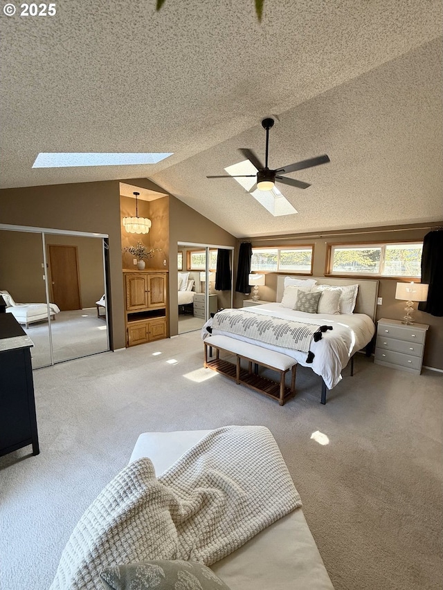 bedroom with carpet, lofted ceiling with skylight, and a textured ceiling