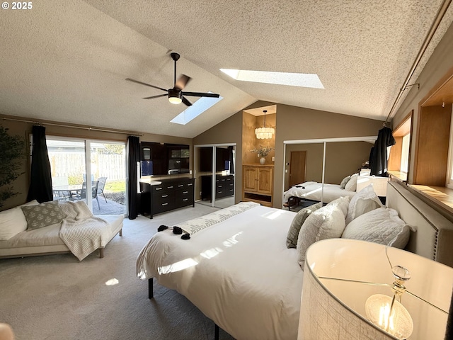 bedroom featuring light carpet, vaulted ceiling with skylight, a textured ceiling, access to exterior, and ceiling fan