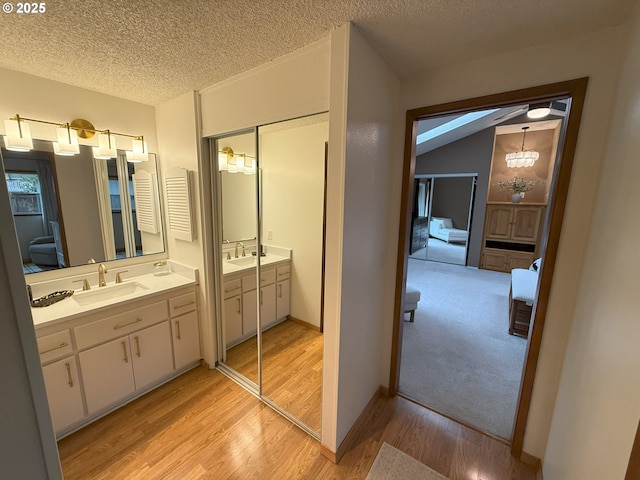 bathroom with two vanities, ensuite bathroom, a sink, and wood finished floors