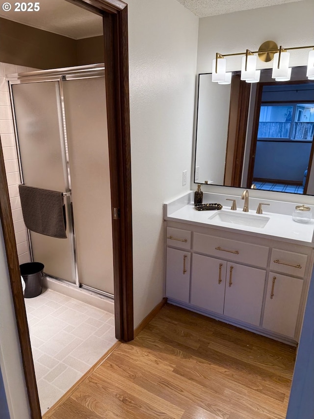 full bathroom with vanity, a stall shower, and wood finished floors