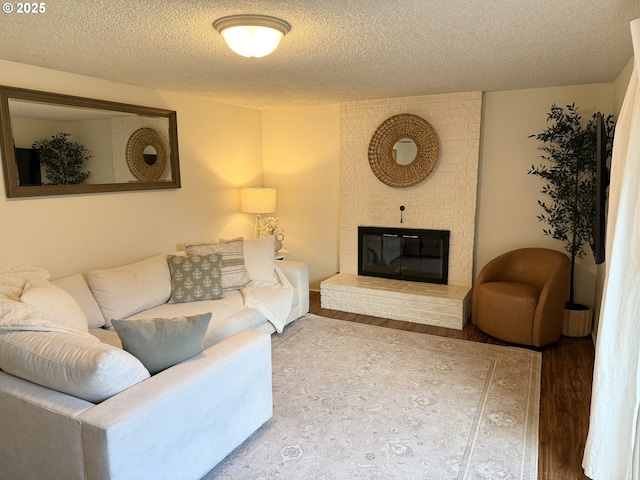living area with wood finished floors, a brick fireplace, and a textured ceiling