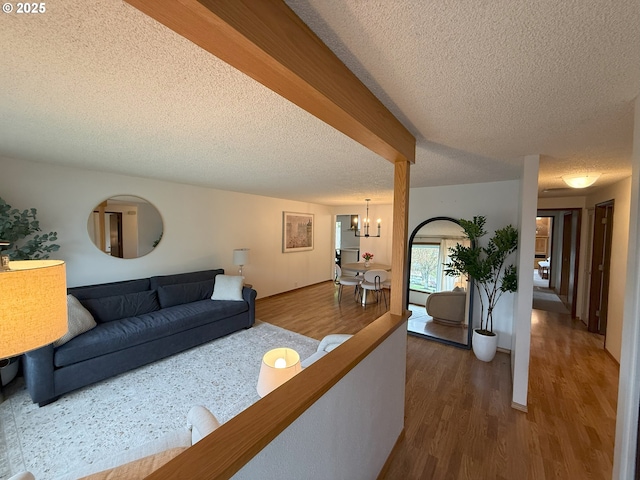 living room with dark wood-type flooring, a notable chandelier, and a textured ceiling