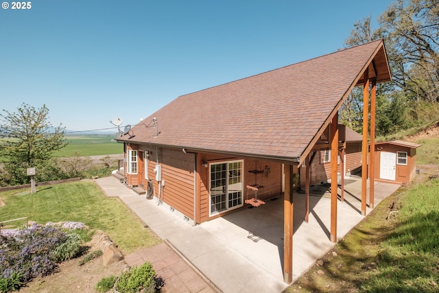 view of side of home featuring an outdoor structure, a yard, a patio, and a storage shed